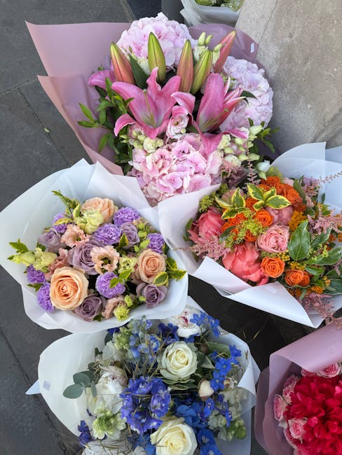 A collection of five floral bouquets arranged for flower delivery, featuring a variety of colorful fresh flowers. The central bouquet prominently displays pink lilies, pale pink hydrangeas, and green